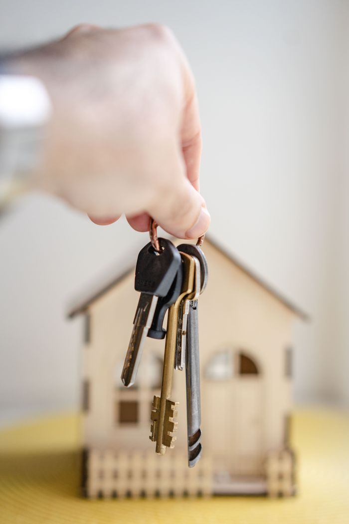 Mastering the First Impression: Your intriguing post title goes here Crop faceless real estate agent with keys from new house bought with mortgage against wooden model of building
